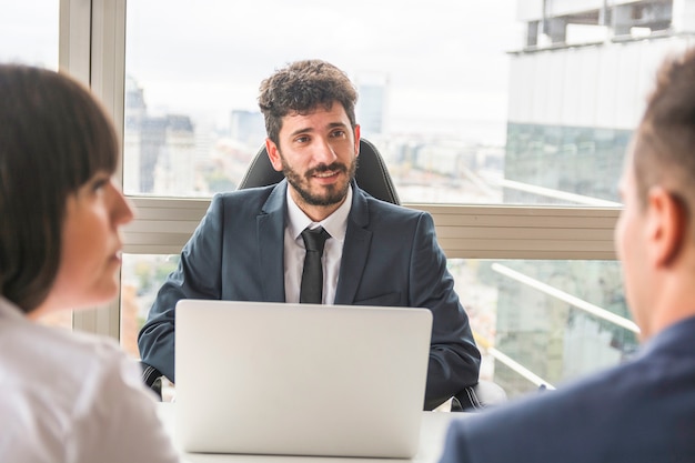 Encargado de sexo masculino que habla con los empresarios en el lugar de trabajo