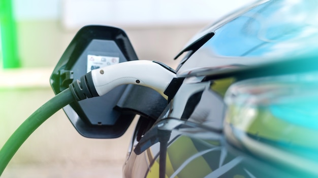 Enchufado el cargador a un coche eléctrico en la estación de carga