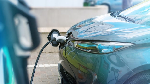 Enchufado el cargador a un coche eléctrico en la estación de carga