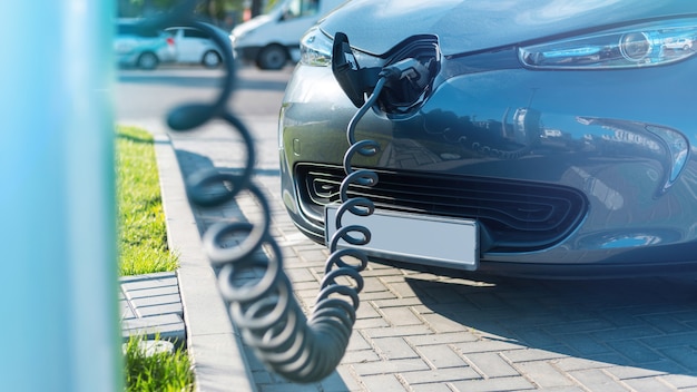 Enchufado el cargador a un coche eléctrico en la estación de carga