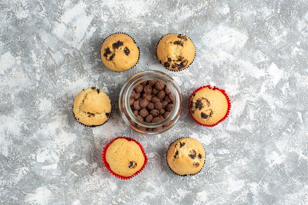 Por encima de deliciosos cupcakes pequeños alrededor de galletas de chocolate en una olla de vidrio sobre la superficie del hielo