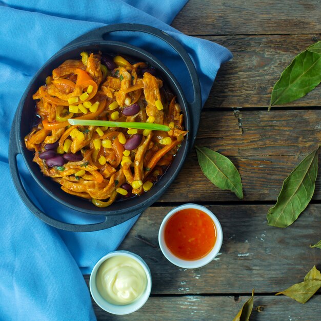 encima el guiso de pollo con verduras y callos en una sartén servido con salsa de chile dulce