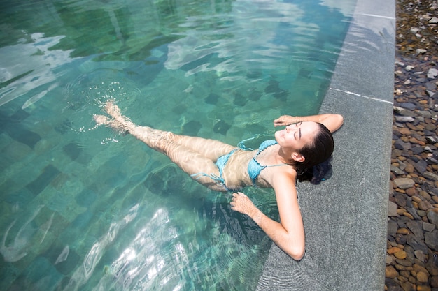 Por encima de la vista de la mujer feliz disfrutando descansando en la piscina