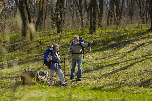 Encuentra el camino correcto en la vida. Pareja de familia de hombre y mujer en traje de turista caminando en el césped verde en un día soleado cerca del arroyo. Concepto de turismo, estilo de vida saludable, relajación y convivencia.