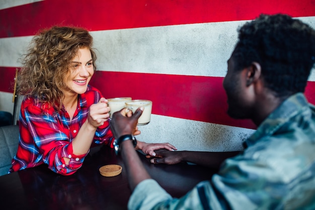 Foto gratuita encuentro de dos estudiantes, bebiendo café con leche y divirtiéndose. estudiantes durante el recreo en el café.