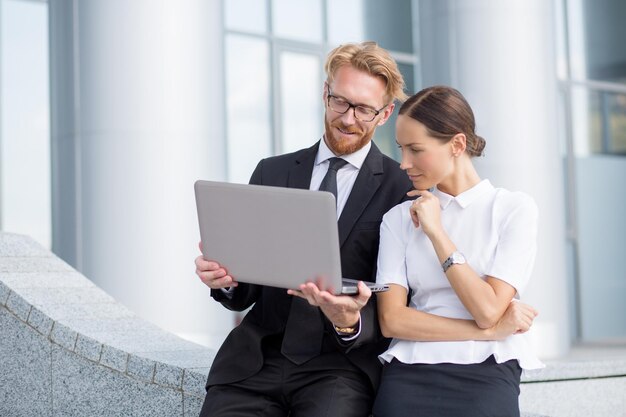 Encuentro de empresarios. Hombre pelirrojo con gafas manteniendo portátil y mostrando algo de mujer bonita en la pantalla.