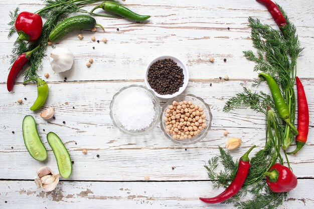 Encurtidos en mesa de madera blanca con pimientos verdes y rojos y ají, hinojo, sal, pimienta negra, ajo, guisantes, primer plano, concepto saludable, vista superior, endecha plana