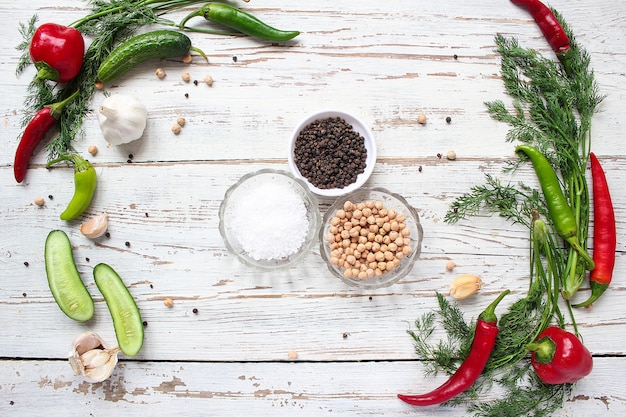 Encurtidos en mesa de madera blanca con pimientos verdes y rojos y ají, hinojo, sal, pimienta negra, ajo, guisantes, primer plano, concepto saludable, vista superior, endecha plana