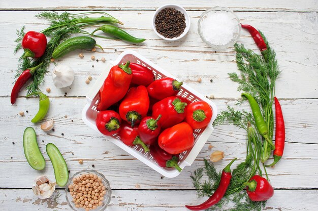 Encurtidos en mesa de madera blanca con pimientos verdes y rojos y ají, hinojo, sal, pimienta negra, ajo, guisantes, primer plano, concepto saludable, vista superior, endecha plana