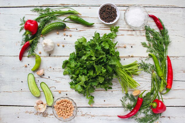 Encurtidos en mesa de madera blanca con pimientos verdes y rojos y ají, hinojo, sal, pimienta negra, ajo, guisantes, primer plano, concepto saludable, vista superior, endecha plana