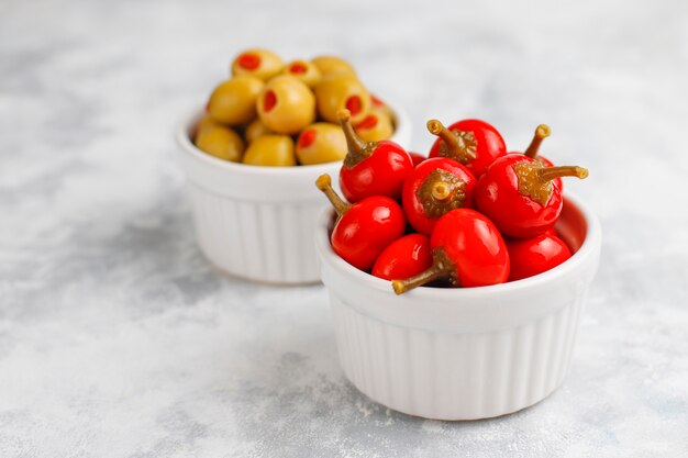 Encurtidos pequeños redondos red hot cherry chili peppers sobre hormigón gris