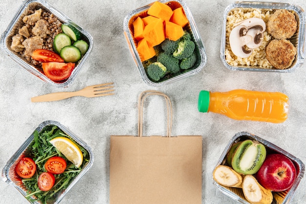 Foto gratuita endecha plana de bolsa de papel con comidas en guisos y jugo de naranja