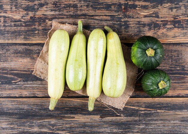 Endecha plana calabacines blancos y verdes en la mesa de madera oscura