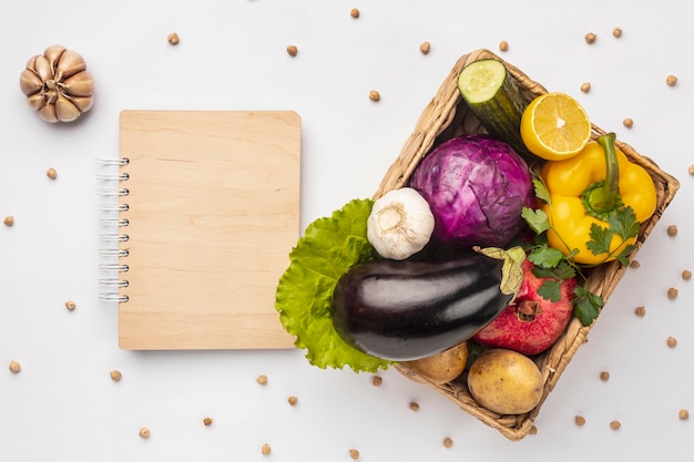 Endecha plana de canasta de verduras frescas con cuaderno