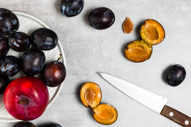 Endecha plana de ciruelas y manzana sobre fondo de madera