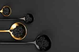 Foto gratuita endecha plana de cucharas doradas y negras con caviar