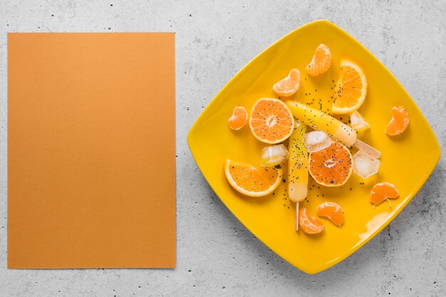 Endecha plana de deliciosas paletas en plato con naranja y espacio de copia