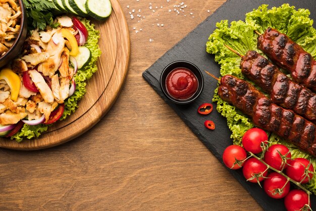 Endecha plana de delicioso kebab en pizarra con otros platos y salsa de tomate