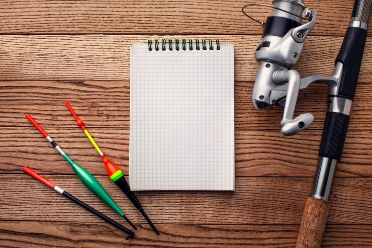 Foto gratuito endecha plana de elementos esenciales de pesca con cuaderno