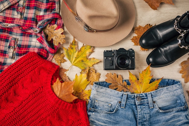 Endecha plana de estilo y accesorios de mujer, suéter de punto rojo, camisa a cuadros, jeans, botas de cuero negro, sombrero, tendencia de la moda de otoño, vista desde arriba, ropa, hojas amarillas