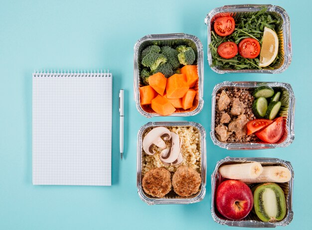 Endecha plana de guisos con comidas y cuaderno