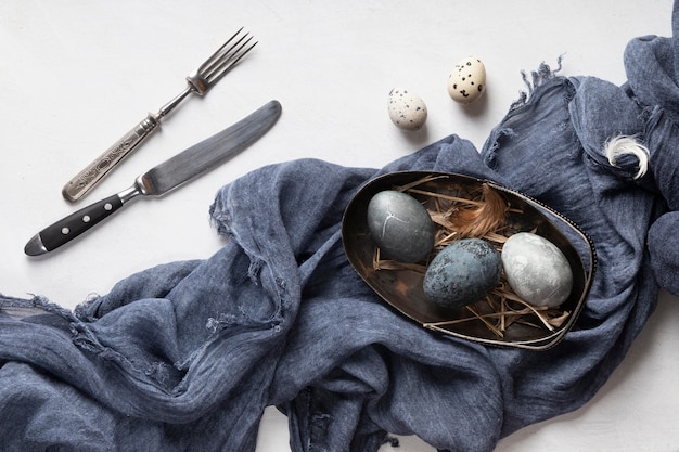 Endecha plana de huevos de pascua con cubiertos y textiles