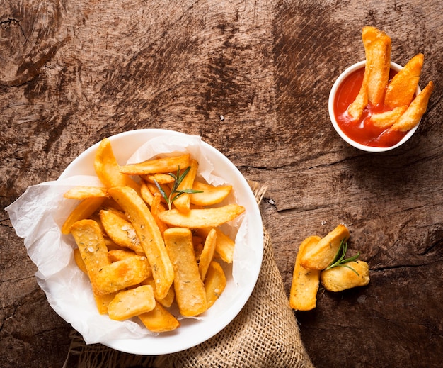 Endecha plana de papas fritas en un plato con tazón de salsa de tomate