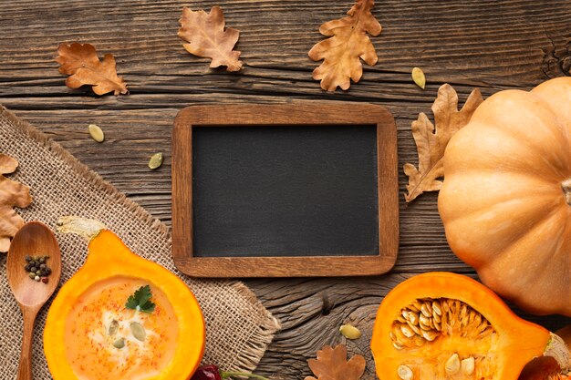 Endecha plana en rodajas de calabaza cuchara de madera y hojas con pizarra en blanco