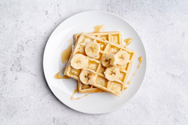 Endecha plana de rodajas de plátano y miel sobre waffles