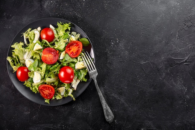 Endecha plana sabrosa ensalada fresca en plato negro con espacio de copia