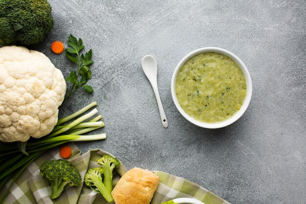 Endecha plana sopa de brócoli en un tazón de verduras y cuchara