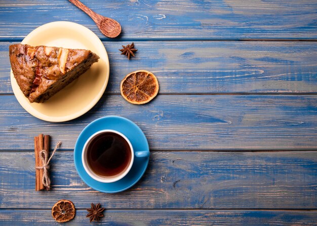 Endecha plana de taza de té y rebanada de pastel