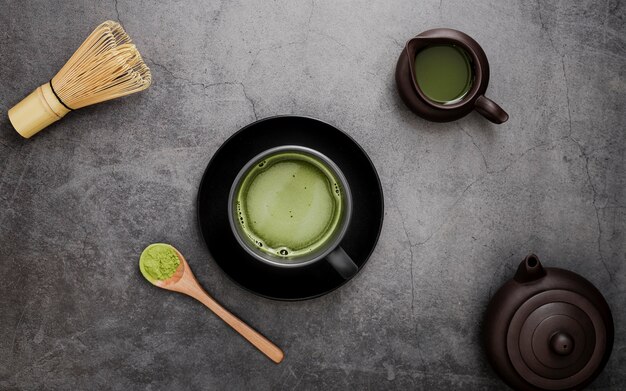 Endecha plana de té matcha en taza en plato con batidor de bambú