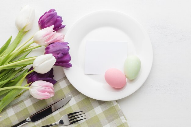 Endecha plana de tulipanes bellamente coloreados con plato y huevos de pascua