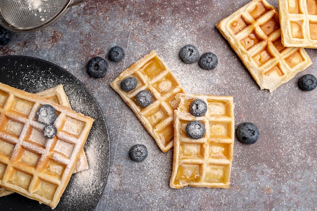 Foto gratuita endecha plana de waffles con azúcar en polvo encima y arándanos