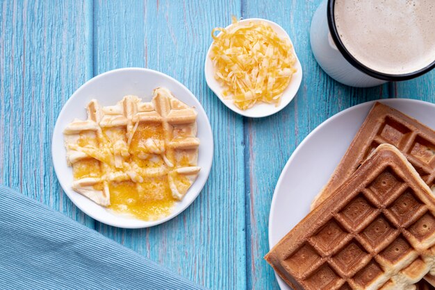 Endecha plana de waffles en un plato con queso derretido y bebidas