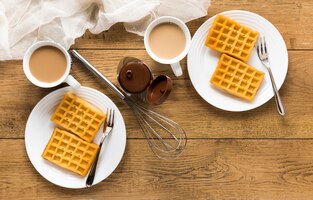 Foto gratis endecha plana de waffles en platos con batidor y café