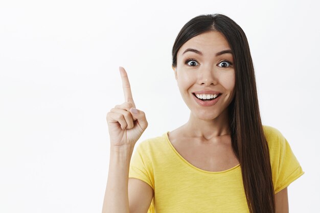 Energizado joven genio femenino creativo con amplia sonrisa blanca levantando el dedo índice en gesto eureka