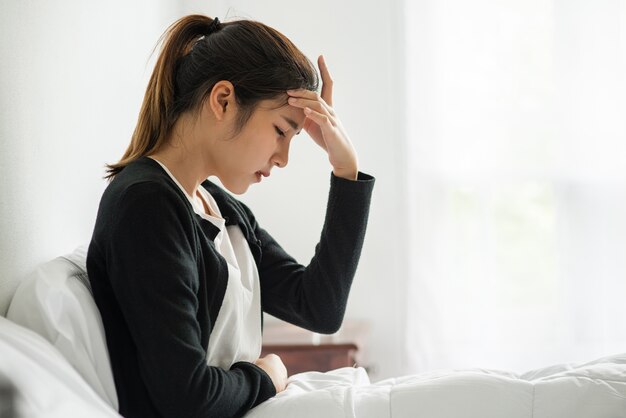 La enferma tenía dolor de cabeza y las manos le tocaban la cabeza en la cama.