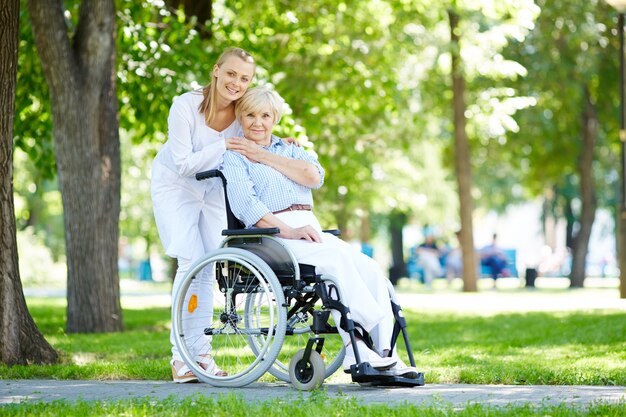 Enfermera abrazando a la anciana en silla de ruedas