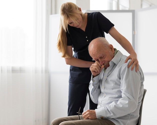 Enfermera consolando anciano llorando