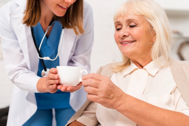 Enfermera dando té al primer plano de la anciana