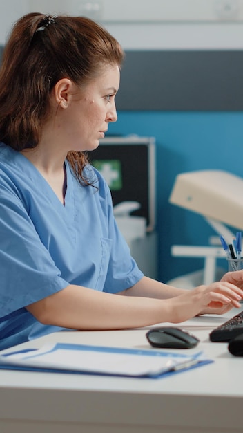 Foto gratuita enfermera escribiendo en el teclado de la computadora para consulta y cita. asistente médico con tecnología para el sistema sanitario en el consultorio médico. especialista que trabaja con equipos médicos.