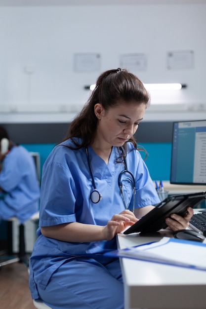 Enfermera farmacéutica mirando tablet PC analizando experiencia en enfermedad