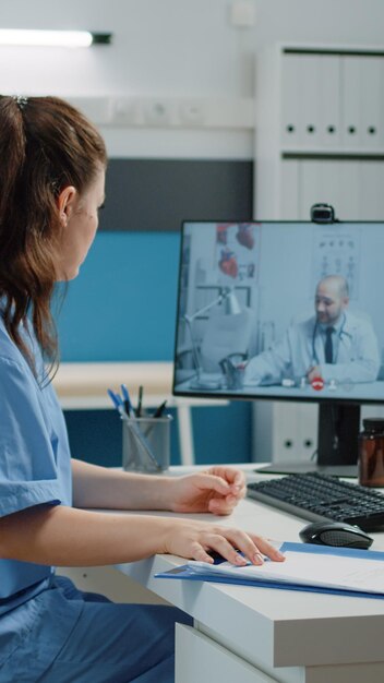 Enfermera hablando con el médico en una videollamada para obtener asesoramiento profesional en el gabinete. Asistente médico que usa una conferencia en línea con un especialista para consulta y visita de control. Sistema de Cuidado de la Salud