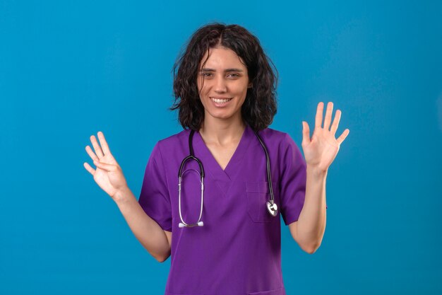 Enfermera joven en uniforme médico y con estetoscopio sonriendo mostrando ambas manos palmas abiertas de pie