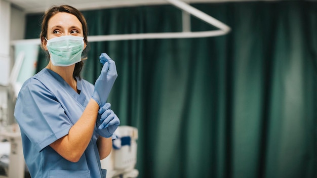 Enfermera con una máscara poniéndose guantes preparándose para curar a un paciente con coronavirus