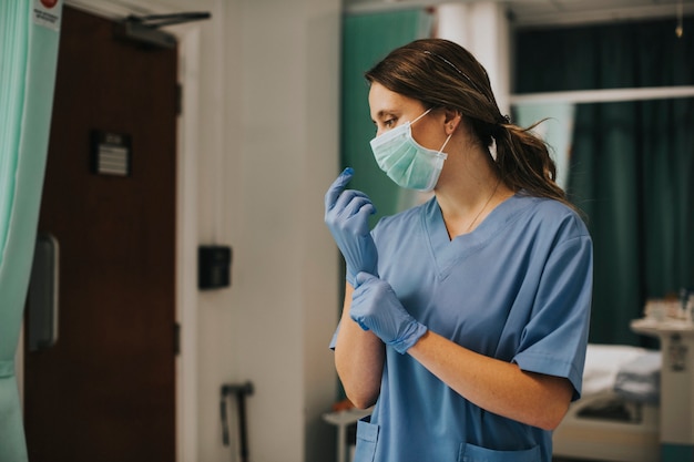 Foto gratuita enfermera con una máscara poniéndose guantes