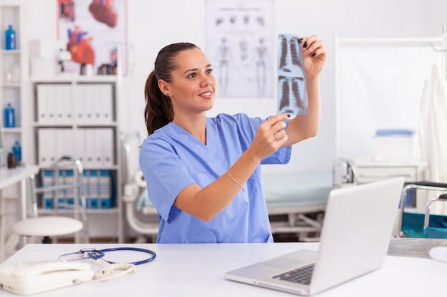 Enfermera médica con radiografía del paciente en la oficina del hospital. Radiólogo en uniforme médico sosteniendo y mirando rayos x, examen, hueso, médico, análisis, diagnóstico.