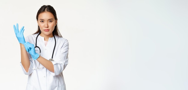 Foto gratuita una enfermera médica segura de sí misma se puso guantes médicos de goma para el puesto de examen clínico del paciente